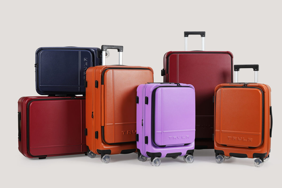 Six TRVLR front-opening cases in Wine, Cognac, Orchid and Nordic, stacked and standing together